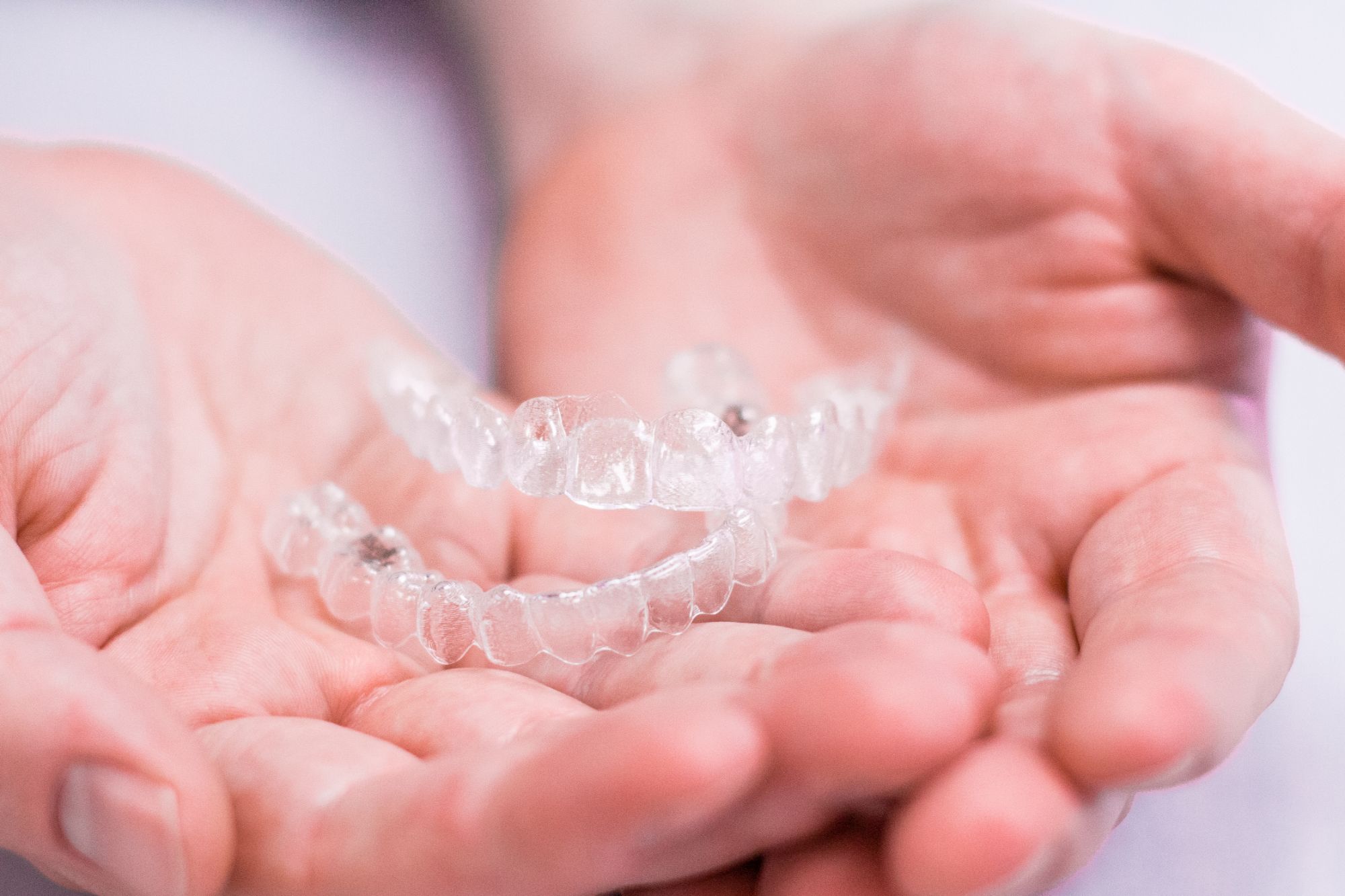 Hands holding clear aligners